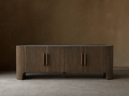 Astor Media Console with oak wood reeding, soft-close doors, and wooden pulls with brass accents. Inset marble top.