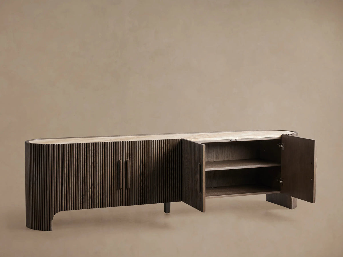 Astor Media Console. Dark brown oak console with reeded front, rounded ends, light marble top, and two vertical wooden pulls.