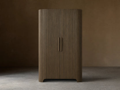 Front view of the dark oak Astor Cabinet with vertical reeding, rounded sides, and two vertical wooden pulls.