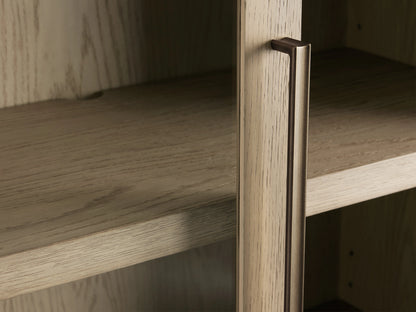 Close-up of Bodhi Cabinet showing solid white oak veneer with subtle grain patterns, brass handle, and two adjustable shelves.
