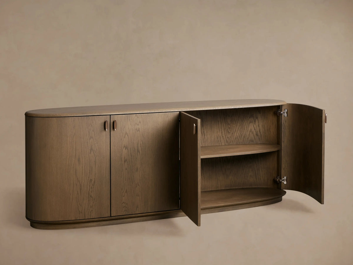 Bexler Sideboard, Abanos finish. Curved oval shape with left doors closed, right doors open revealing two interior wood shelves.