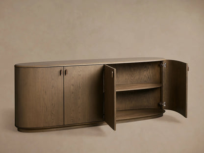 Bexler Sideboard, Abanos finish. Curved oval shape with left doors closed, right doors open revealing two interior wood shelves.