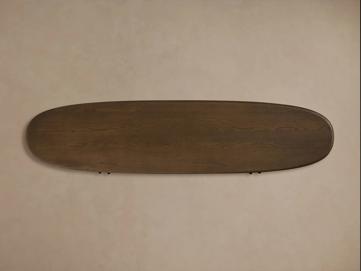 Top view of a dark brown, oval-shaped Bexler Sideboard with visible wood grain, set against a light beige wall.