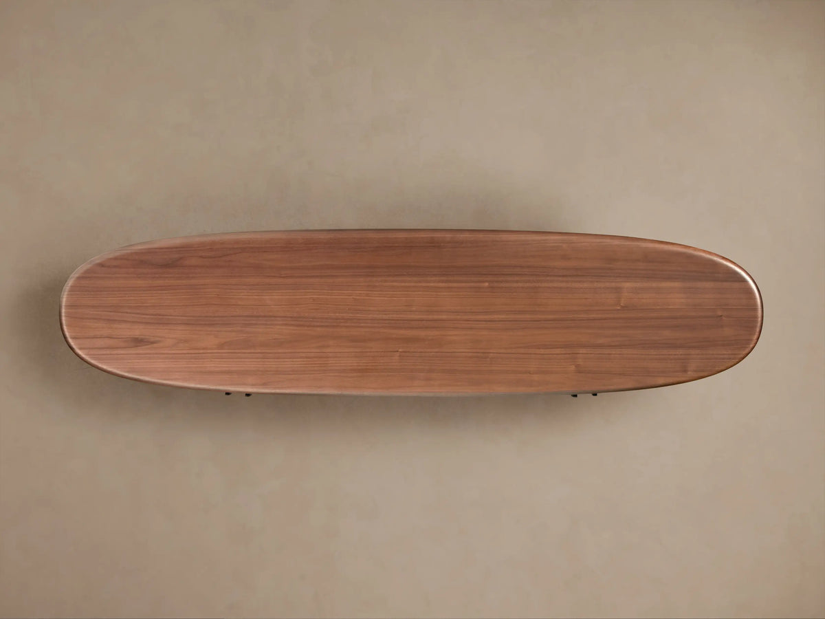 Top-down view of the Bexler Sideboard, featuring a smooth, oblong dark brown walnut wood top with rounded edges, mounted on a tan wall.