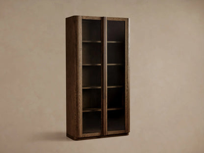 Tall Bardot Cabinet made of dark oak, with two glass-paneled doors, bronze handles, and internal shelves.