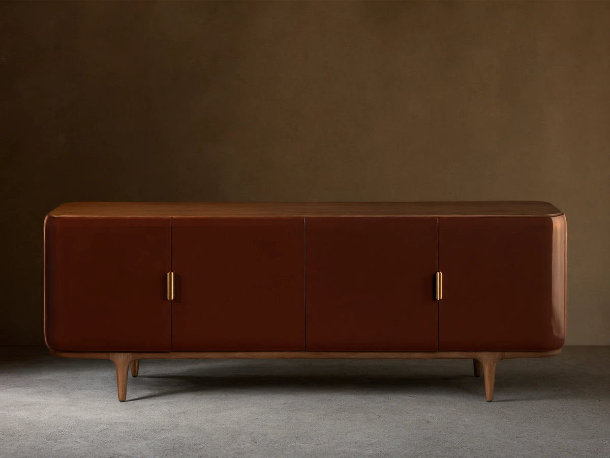 Front view of the Bryer Media Console, with oxblood lacquer finish, walnut top and base, and champagne brass handles.