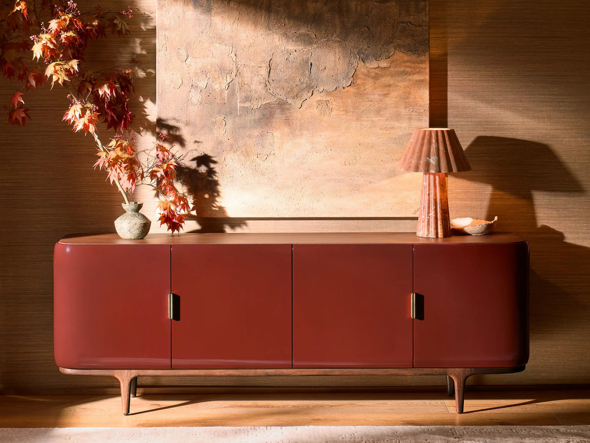 Front view of the Bryer Media Console, with oxblood lacquer finish, walnut top and base, and champagne brass handles.