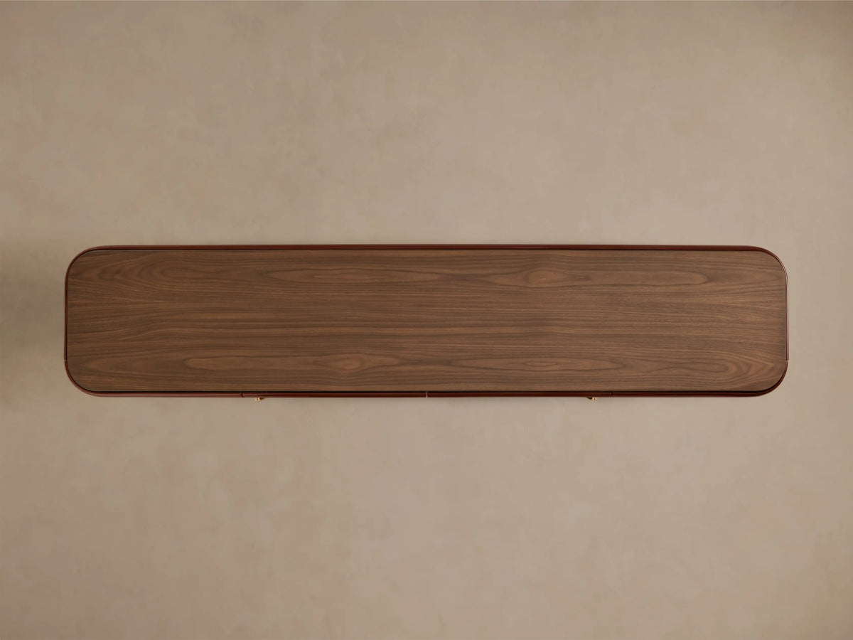 Close-up of the oxblood Bryer Media Console, showing its walnut-finished top and champagne brass hardware.