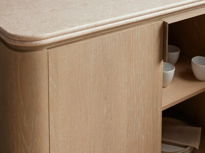 Caden Sideboard in a sand wood finish with a cream stone top, four doors, and brushed nickel handles and plinths.