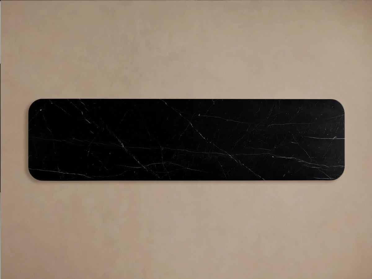 Close-up of Caden Sideboard with a black marble top, curved walnut wood base. A door is ajar, showing clear glasses and bowls inside.