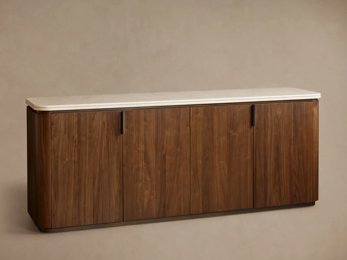 Caden Sideboard with dark walnut wood veneer, four doors, and a cream stone top, centered against a taupe wall and wood floor.