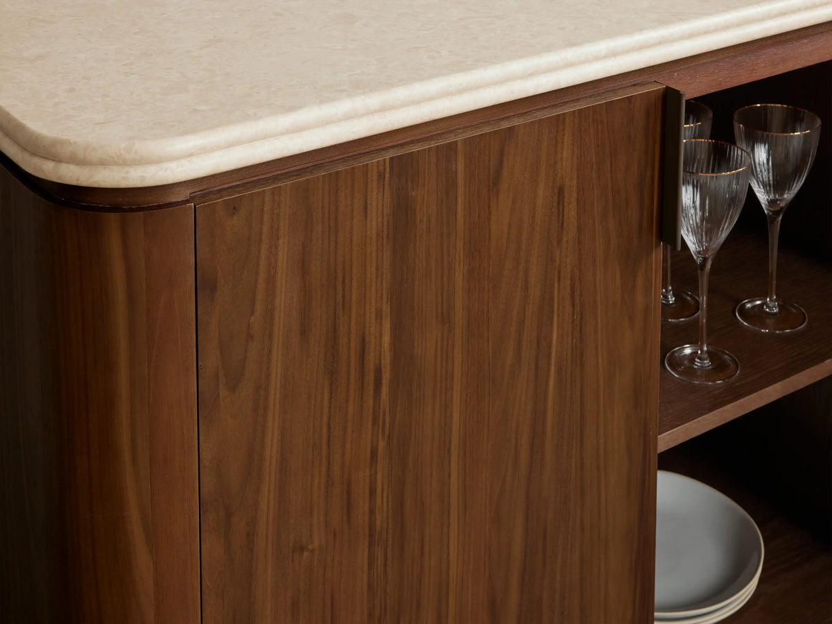 Long Caden Sideboard in dark walnut wood veneer, with four doors, antique bronze handles, and a cream stone top.