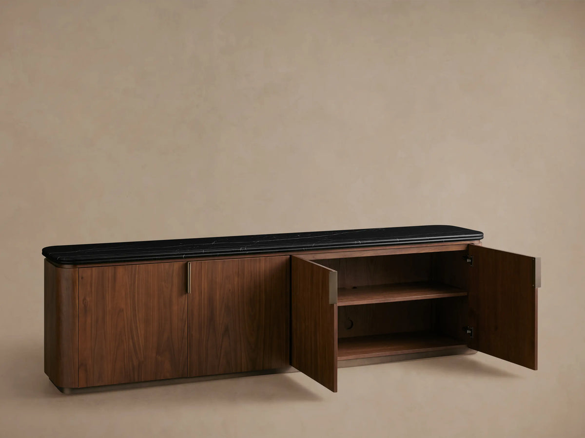 Front view of Caden Media Console: walnut wood cabinet with rounded edges, black stone top, and two bronze handles.
