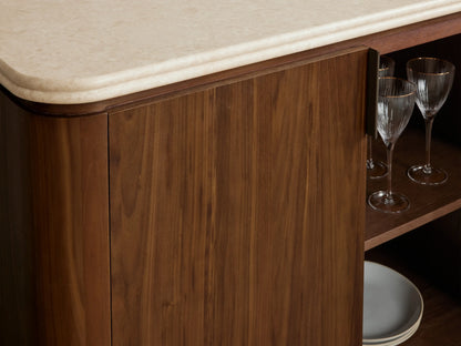 Caden Sideboard, dark walnut wood with rounded cream stone top. Four doors, antique bronze pulls, on wood floor.