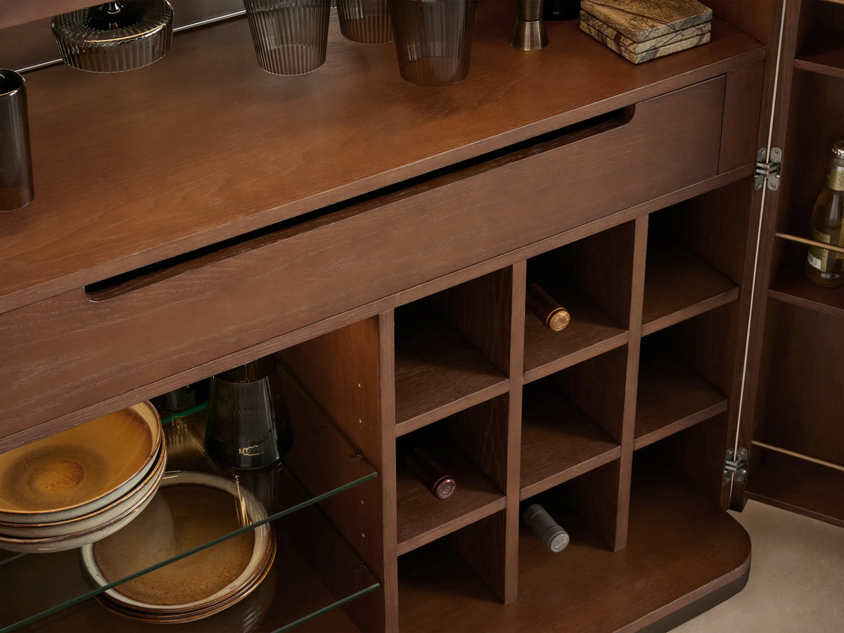 Interior of Caden Bar Cabinet with antique bronze stemware rack, hanging dark glasses, warm LED light, and walnut wood.