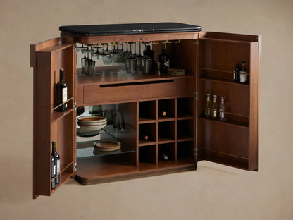Interior of dark walnut Caden Bar Cabinet with barware, a drawer, glass shelves holding plates, and wine grid with bottles.
