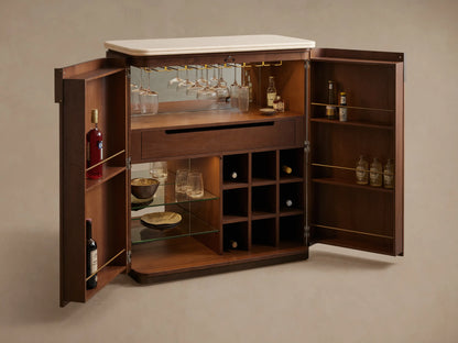 Caden Bar Cabinet in dark walnut veneer with rounded edges, cream stone top, and single bronze pull, on wood floor.