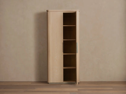 Caden Cabinet in light sand-finished American walnut wood. One door ajar, showing shelves, rounded edges & plinth base.
