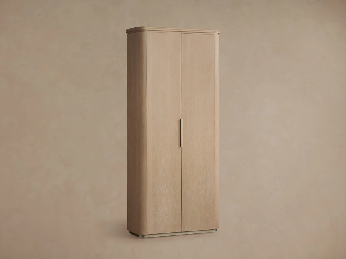 Light sand wood Caden Cabinet, tall with two doors, dark vertical handle, rounded corners, and a low plinth base.