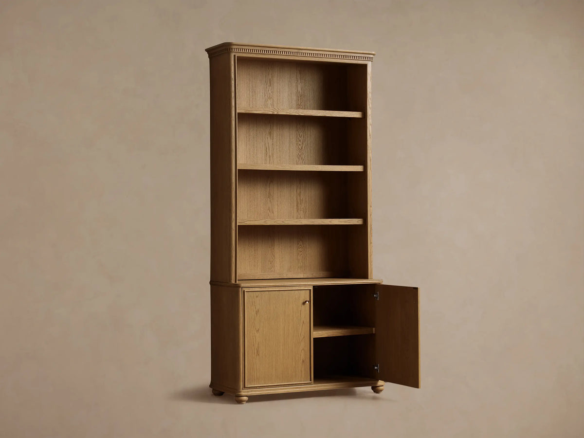 Close-up of Carlisle Hutch's interior, showing light oak shelves styled with stacked books, a white jar, brass cup, and metallic bookend.
