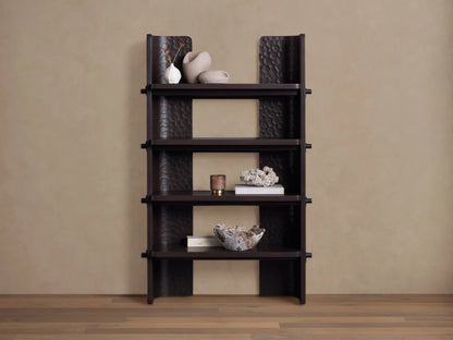 Dark brown chiseled bookcase made of handcrafted mahogany wood with four open shelves, standing against a beige wall.