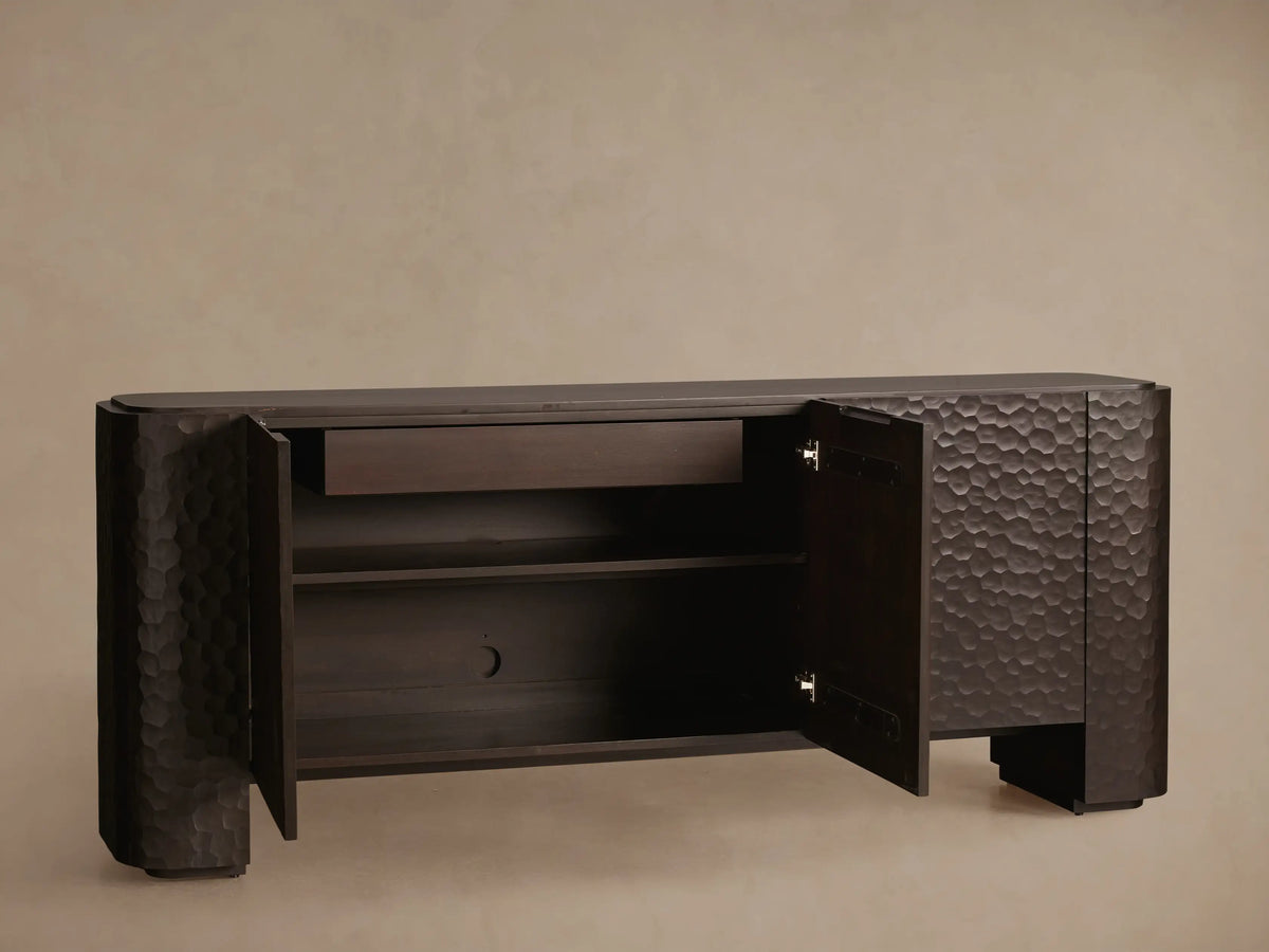 Dark brown Chiseled Sideboard with three textured doors, showcasing carved mahogany and a hand-applied finish on a wooden floor.