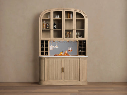 Coventry Bar: Arched light oak wood bar with glass upper doors, mirrored back, marble top, hanging glasses, and fluted lower doors.