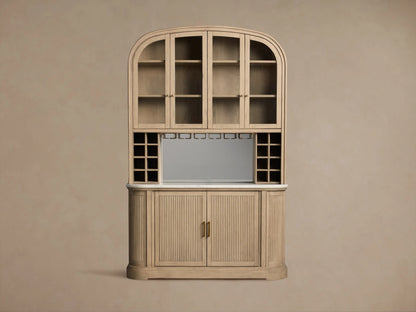 Light oak Coventry Bar with arched glass top cabinets, mirrored middle section with wine racks, white marble counter, and fluted wood base.
