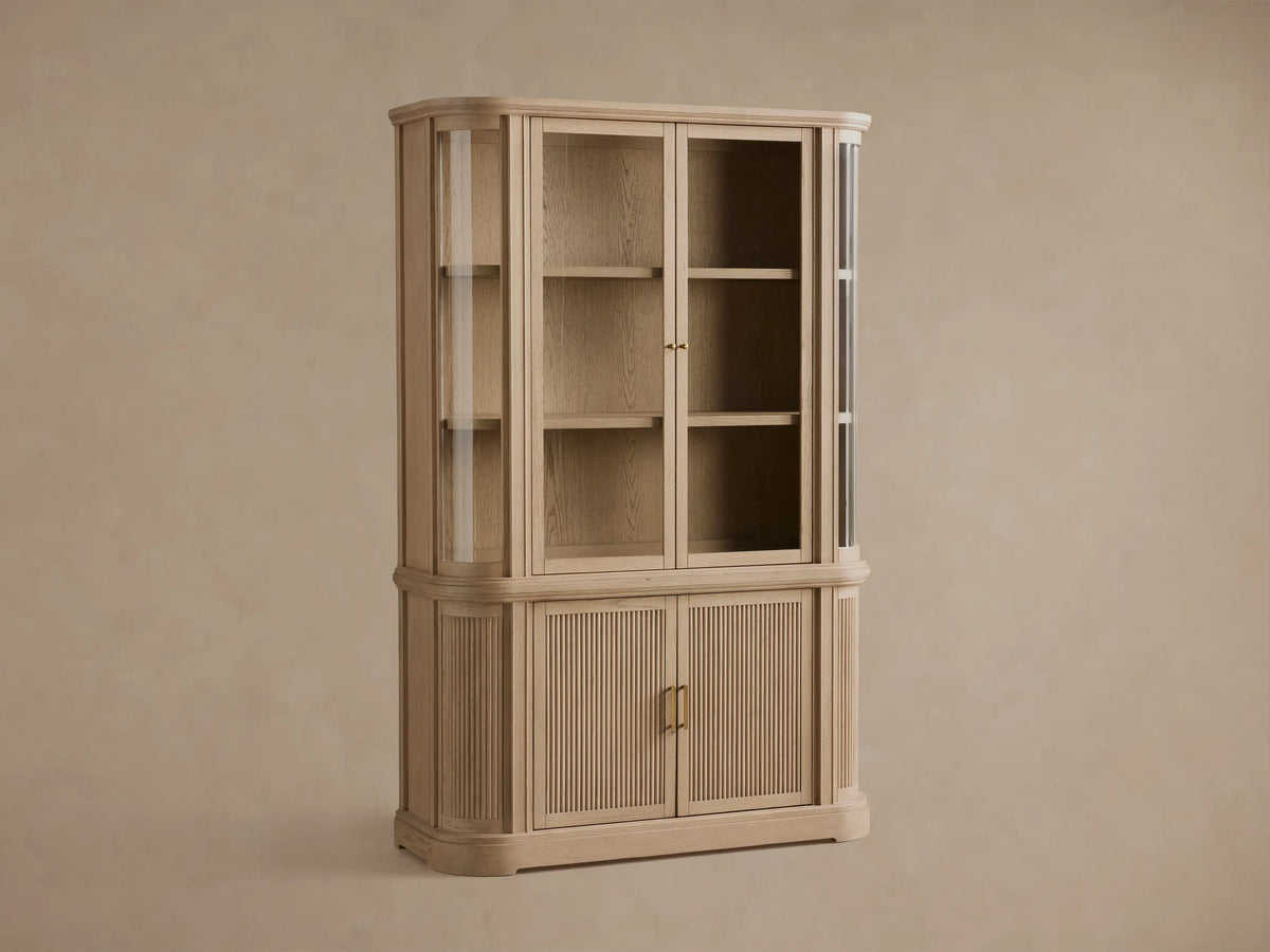 Close-up of Coventry Cabinet in light white oak. Open lower right door shows shelf. Fluted lower left door, antique brass handle.