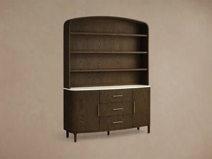 Front view of the dark oak Danny Hutch with Drawers, with an arched top, three open shelves, white marble, three drawers, and brass pulls.
