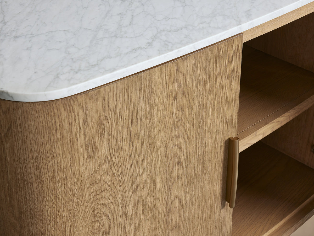 Danny Sideboard in oak wood with fawn finish, featuring a white Carrara marble top. One door is open, showing shelves inside. Brass-finished handles adorn the piece.