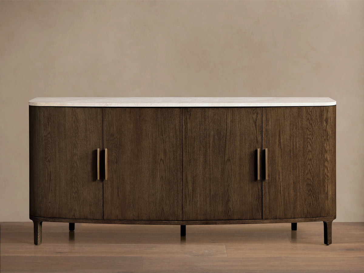 Front view of a dark brown wooden sideboard with a white marble top, curved ends, and four doors featuring gold bar handles.