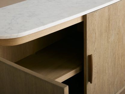 Danny Sideboard in oak wood with a light fawn finish, featuring four doors and brass-finished handles, topped with white marble.