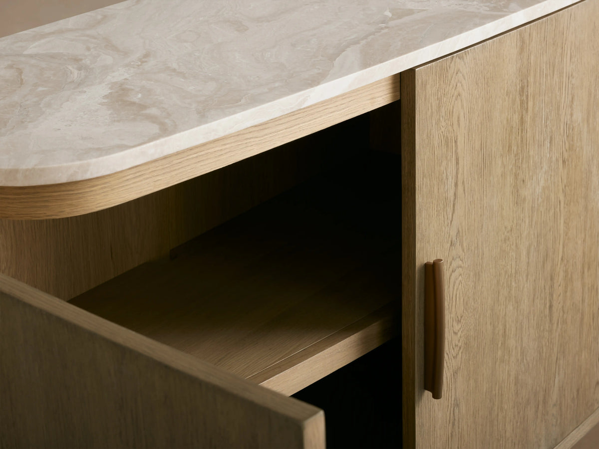 Danny Sideboard with fawn finish, featuring a royal cream marble top. Brass-finished handle on partially open door, revealing a shelf.