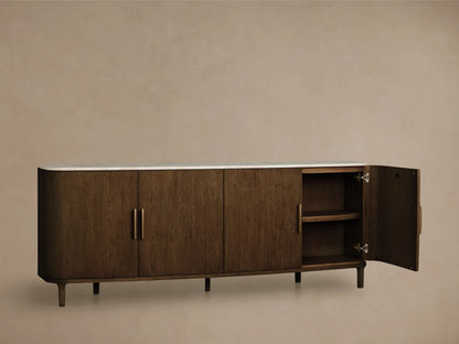 Front view of a dark brown oak wood sideboard with a white marble top, rounded ends, four cabinet doors, and brass bar handles.