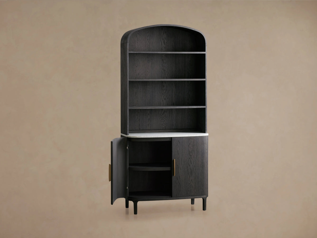 Danny Hutch in ebony finish, featuring a curved top, three shelves, white marble base, and dual-door cabinet with bronze handles.