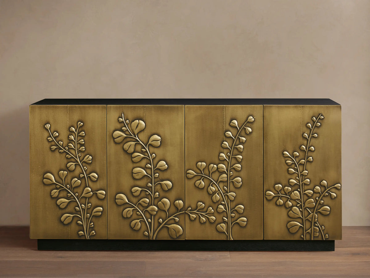 Etasha Sideboard: Brass finish cabinet with black top & base, detailed with intricate carved golden leaf designs on its four doors.