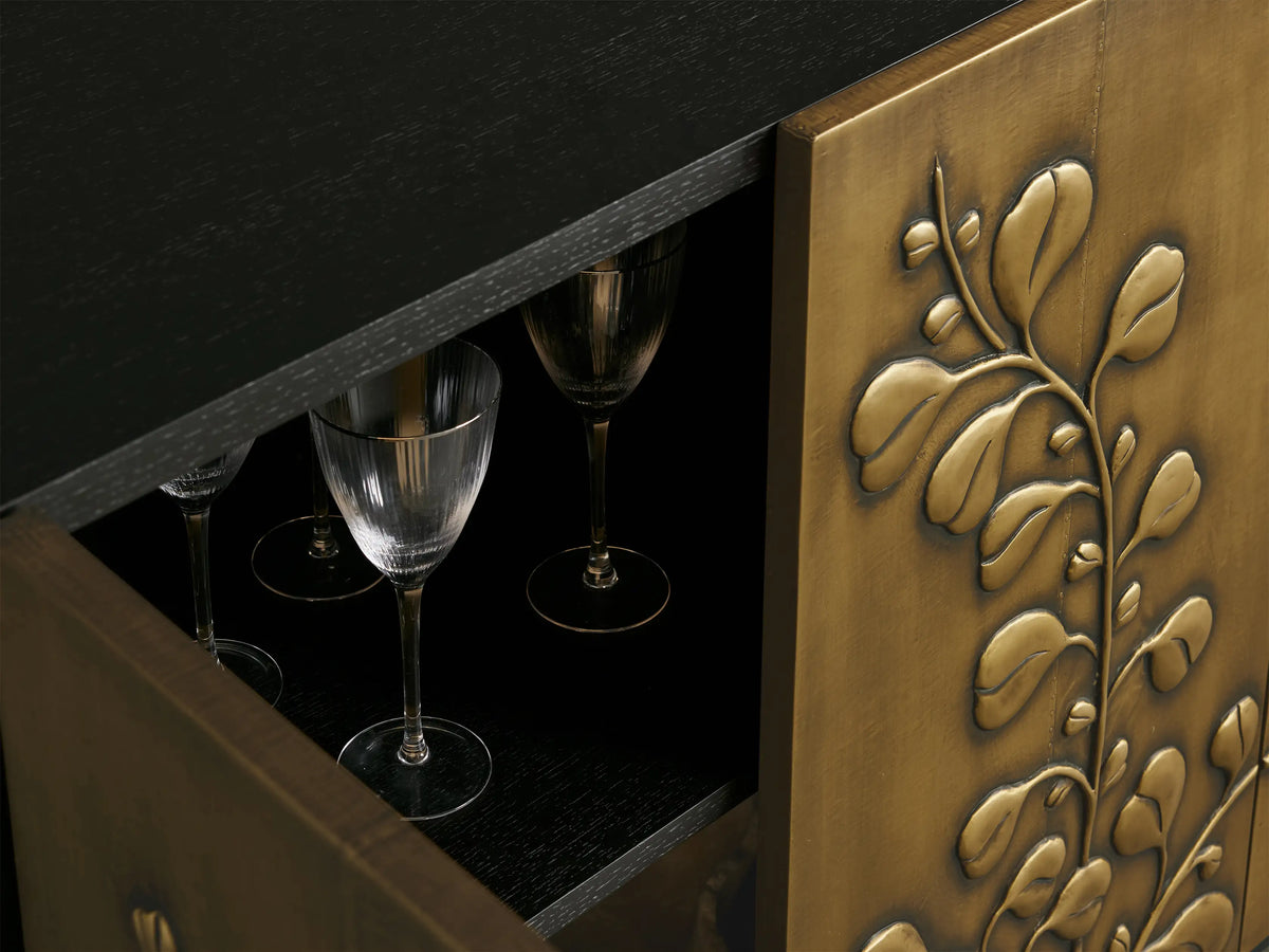 Etasha Sideboard: Brass finish cabinet with black top & base, detailed with intricate carved golden leaf designs on its four doors.