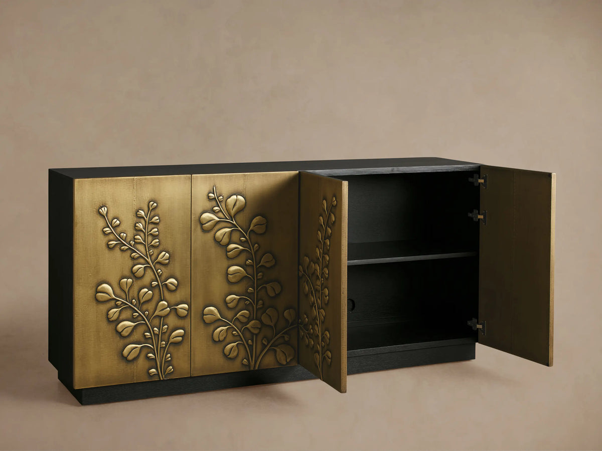 Etasha Sideboard close-up: partly open brass door with carved leaf design, dark ebony interior holding three clear wine glasses.