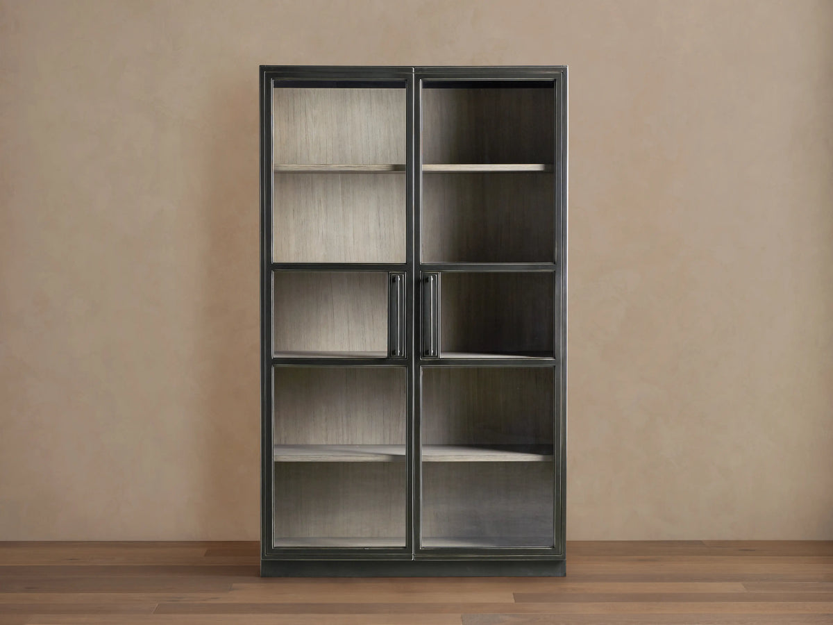 Factory Cabinet with a dark Usine Black finish, displaying tempered glass doors showing visible shelves in a chic grey Stone finish.