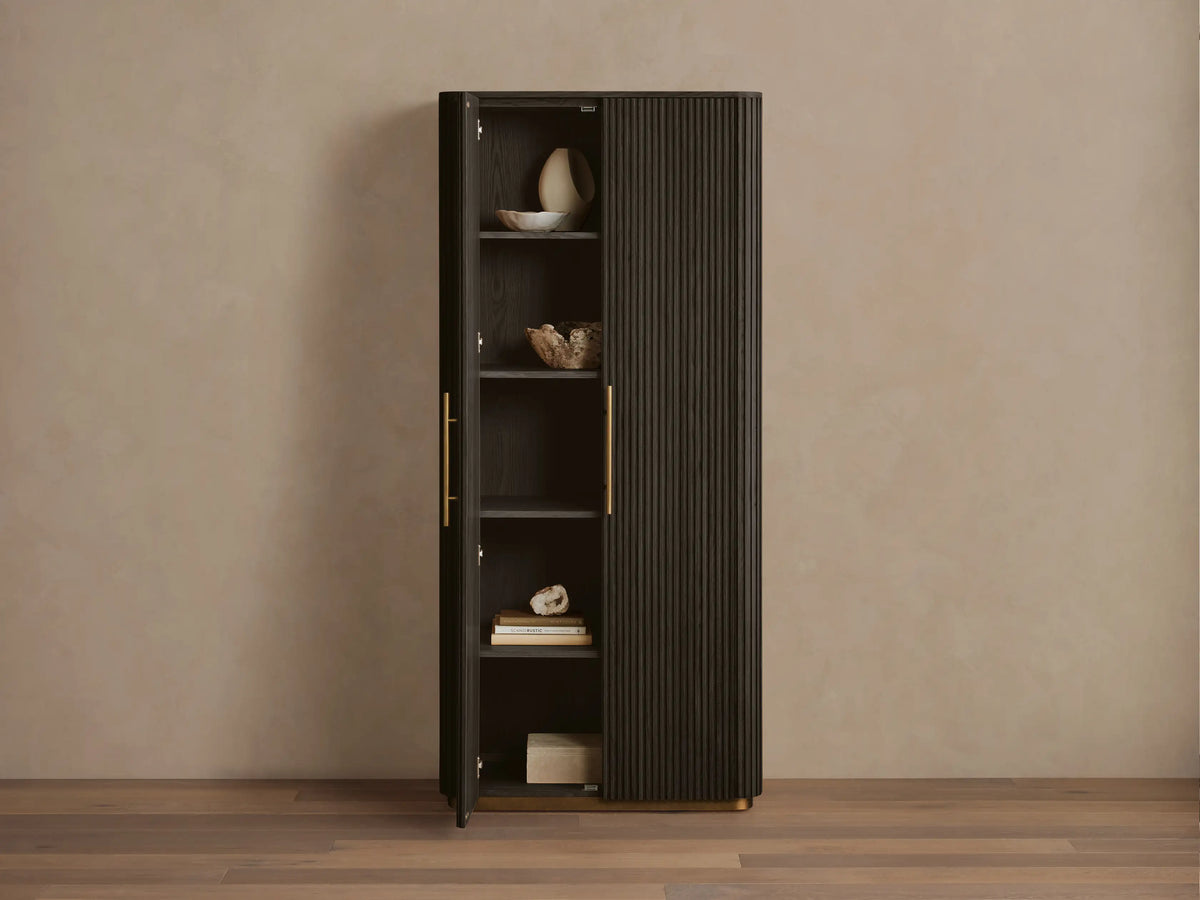 Dark Ebony Finnley Cabinet with fluted right door, brass pulls & plinth base. Left door open, shelves with decor visible.