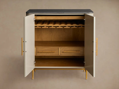 Close-up of open Finnley Bar Cabinet, light beige ribbed door, brass pull, oak interior with wine bottles, 2 hanging glasses.