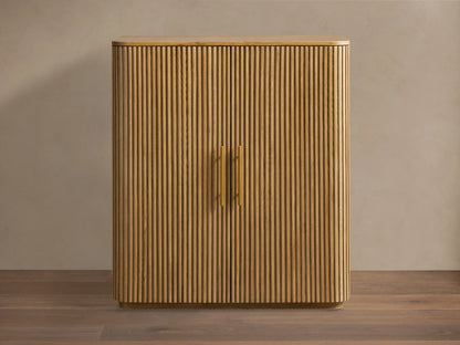 Finnley Wood Bar Cabinet with a honey finish, featuring vertical ribbed design, two central gold handles, and curved edges.