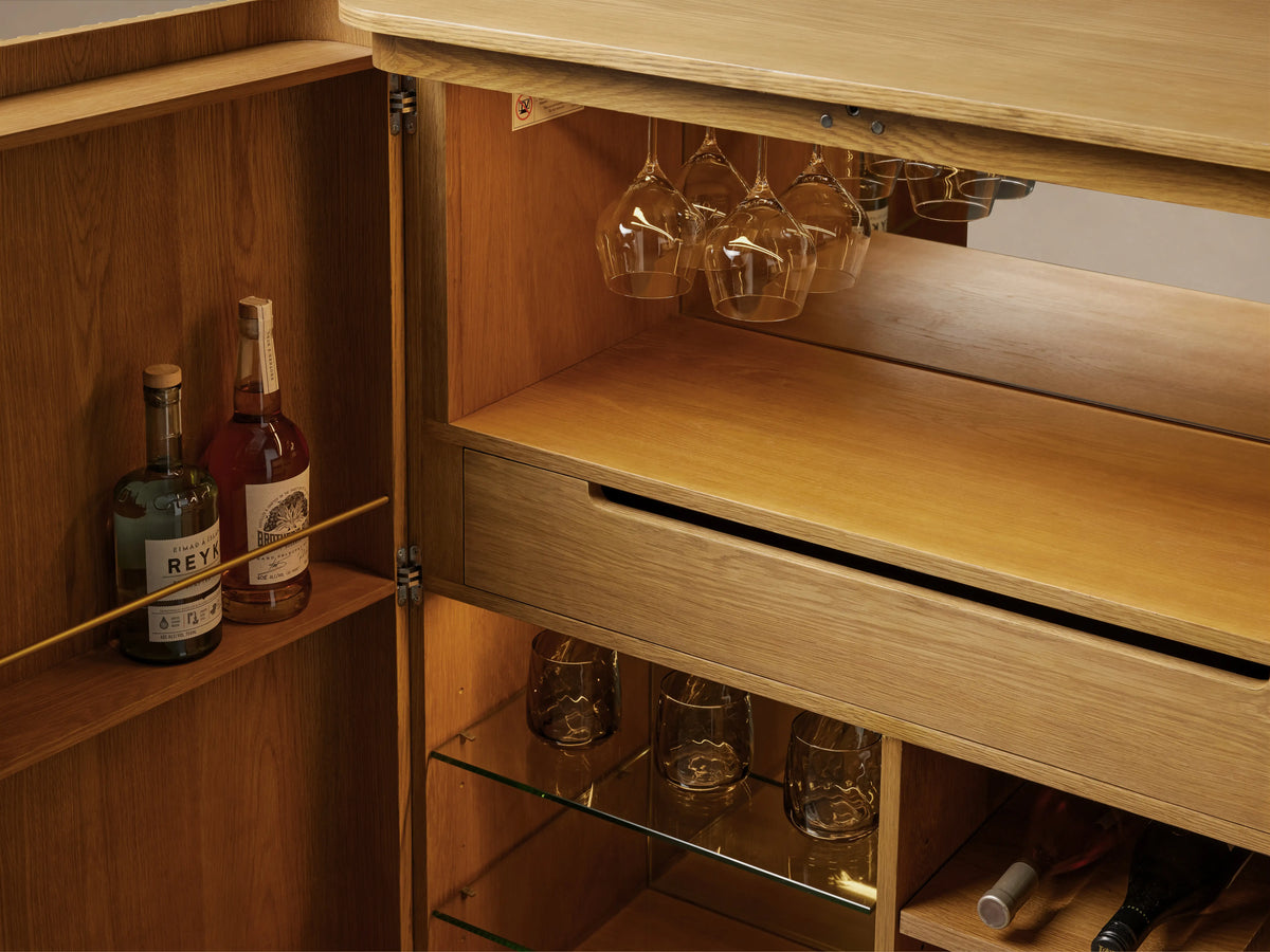 Finnley Wood Bar Cabinet with a honey finish, featuring vertical ribbed design, two central gold handles, and curved edges.