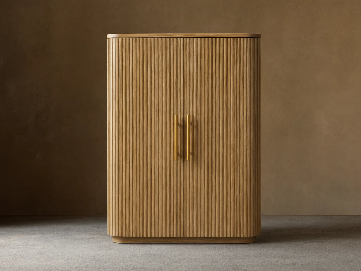 Finnley Wood Bar Cabinet with a honey finish, featuring vertical ribbed design, two central gold handles, and curved edges.