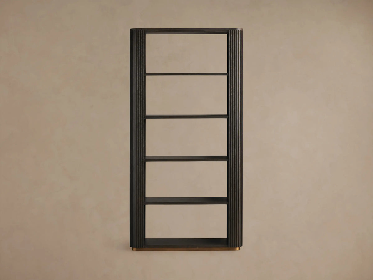 Dark Ebony Finnley Bookcase with fluted side panel. Shelves hold a plant in a stone bowl and two stacked books on a light wall.
