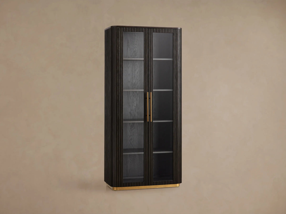 Tall Finnley Glass Cabinet in dark wood with fluted details, two tempered glass doors, brass pulls, and a golden plinth base.