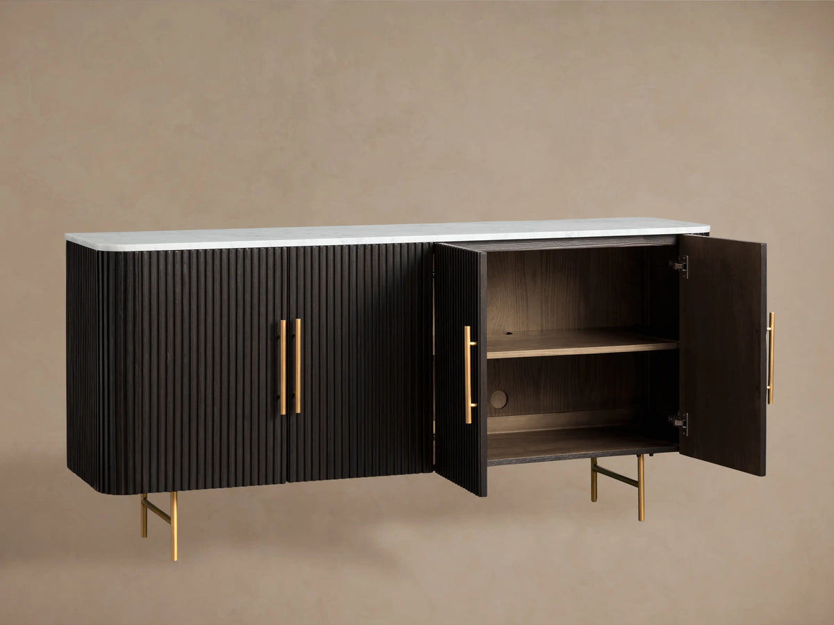 Front view of an Ebony Finnley Sideboard with reeding, a white marble top, and brass-finished handles and legs.