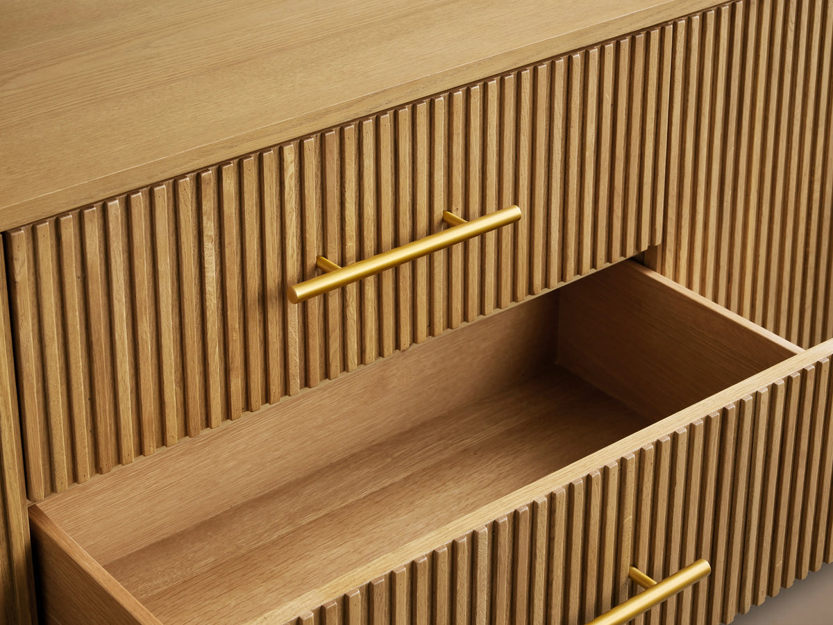 Finnley Wood Sideboard with a Honey finish features vertical grooves, three drawers, two open doors, brass handles, and a subtle sheen.