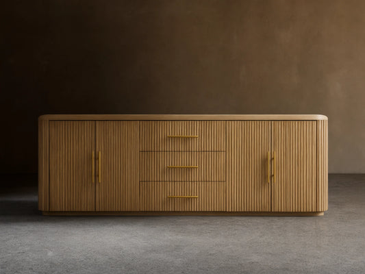 Finnley Wood Sideboard with a honey finish, featuring three central drawers and fluted design doors on each side, with brass-finished handles.